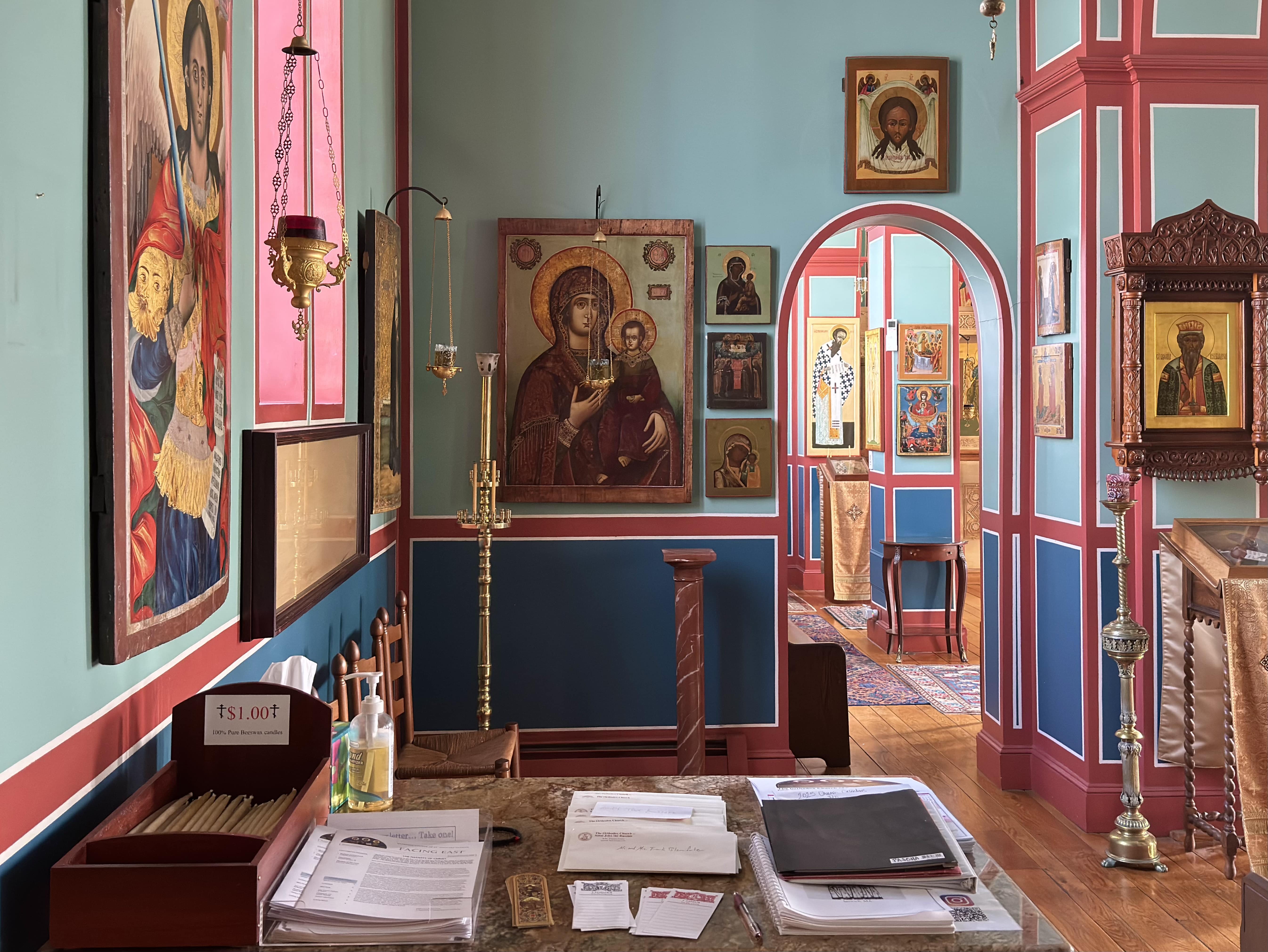 Various icons including a large icon of the Theotokos by the table at the entrance of the church