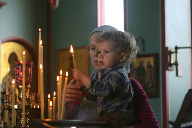 A woman and a child lighting candles in church